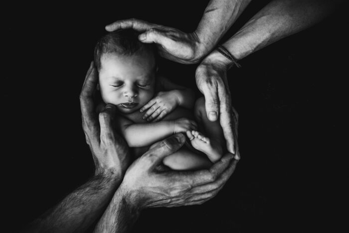 Malutkie dziecko otulone dłońmi dorosłych - ilustracja do Modlitwy Zaufania dr Moniki Gorskiej